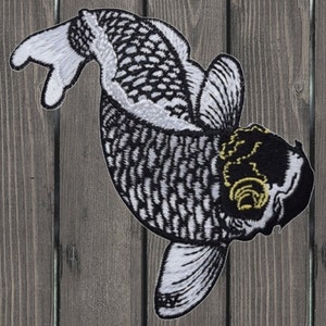 May include: Black and white embroidered koi fish patch with a yellow eye. The fish is swimming to the right and has a detailed scale pattern.