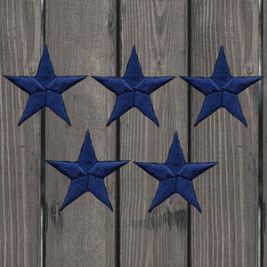 May include: Five dark blue fabric star shapes on a wood background.