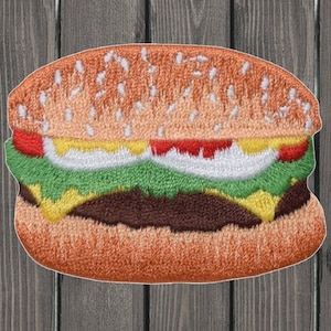 Pode incluir: Etiqueta bordada de um hambúrguer com um pão de gergelim, alface, tomate, queijo e um hambúrguer de carne.