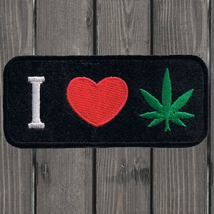May include: Black embroidered patch with the text "I love" in white, a red heart, and a green marijuana leaf.
