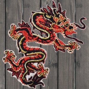 Peut inclure: Écusson brodé représentant un dragon rouge, noir et or. Le dragon est représenté dans une pose dynamique avec des détails complexes. Le patch est destiné aux vêtements ou accessoires.