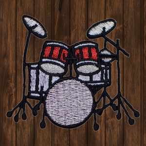 May include: A black and white embroidered patch depicting a drum kit with red and white drums. The patch includes a bass drum, two toms, and two cymbals.