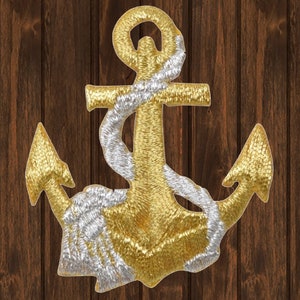 May include: Embroidered anchor patch in gold and silver. The anchor is the primary focus, with a gold body and silver rope detail. The background is a dark brown wood grain.