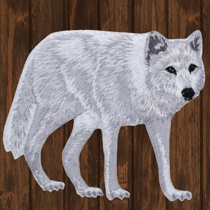 May include: A white wolf with black eyes and a black nose stands on a wooden background. The wolf is facing the right side of the image.