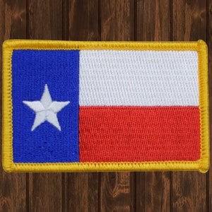 May include: A blue, white, and red embroidered patch with a white star in the blue section. The patch is surrounded by a yellow border.