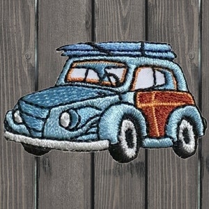 May include: An embroidered patch of a blue vintage car with a surfboard on top. The car has a wood paneling design on the side and white tyres.