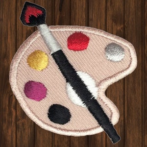 May include: A beige fabric paint palette with a black and white paintbrush. The palette has five paint wells with red, gold, purple, black, and gray paint.
