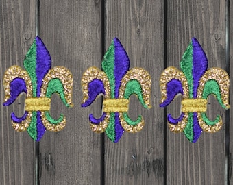 May include: Three gold, green, and purple Mardi Gras fleur-de-lis decorations.