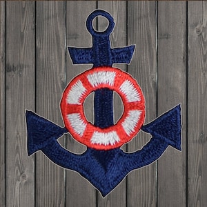 May include: A blue embroidered anchor with a red and white life preserver in the centre. The anchor is on a wood background.