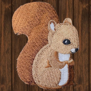 May include: Embroidered patch featuring a detailed squirrel design. The squirrel is depicted in shades of brown, tan, and white, with a fluffy tail and a friendly expression. The patch is likely for clothing or accessories.