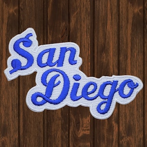 Peut inclure: Écusson brodé blanc avec les mots "San Diego" en lettres cursives bleues.