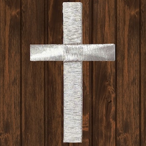 Könnte beinhalten: Ein silbernes Kreuz auf braunem Holzgrund.