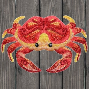 Peut inclure: Patch brodé représentant un crabe rouge et jaune. Le crabe a un design détaillé avec une surface texturée.