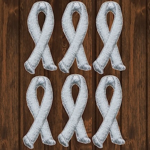 Op de afbeelding: Zes zilveren lintpatches, elk met een lusontwerp. De patches zijn gerangschikt in twee rijen van drie, op een houten achtergrond.