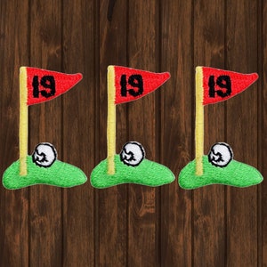 May include: Three embroidered iron-on patches featuring a golf green with a golf ball and a flag with the number 19 on it.
