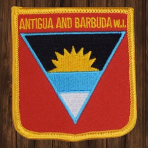 May include: A red, yellow, blue, black, and white embroidered patch with the text "ANTIGUA AND BARBUDA W.I." in black lettering. The patch features the flag of Antigua and Barbuda.