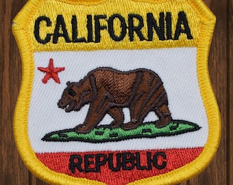 May include: A yellow, red and white embroidered patch with the words "CALIFORNIA REPUBLIC" and a brown bear with a red star.