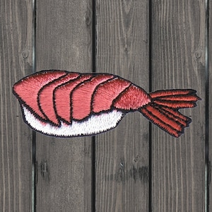 May include: A red embroidered sushi patch with a white rice section and a shrimp tail.