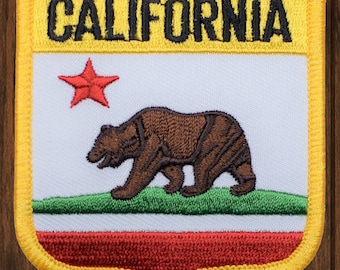 May include: A yellow embroidered patch with the words "CALIFORNIA" in black lettering. The patch features a red star, a brown bear walking on a green field, and a red, white and green stripe.