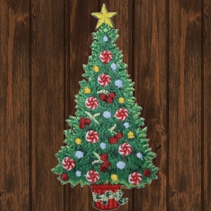 Könnte beinhalten: Ein grüner Filz-Weihnachtsbaum mit einem gelben Stern oben. Der Baum ist mit roten und weißen Zuckerstangen, roten Beeren, gelben Kugeln und blauen Kugeln geschmückt. Der Baum steht in einem roten Topf mit einem grünen Band.