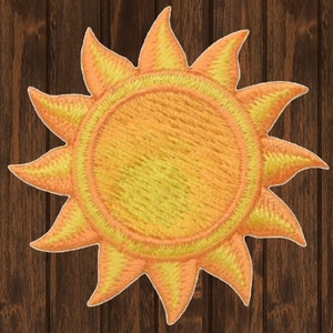 May include: An embroidered sun with a textured surface. The sun is yellow and orange and has 12 rays.