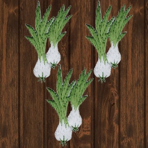May include: Three sets of green onion embroidery patches. Each set has two green onions with white bulbs. The patches are on a brown wooden background.