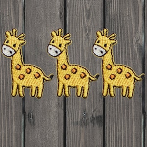 Pode incluir: Três patches de ferro bordados amarelos de girafas com manchas marrons. As girafas estão viradas para a direita e têm um design simples.