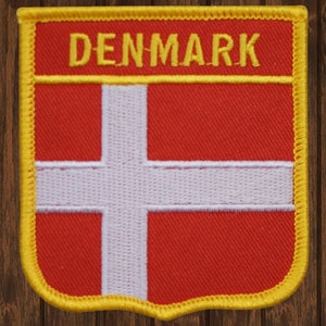Puede incluir: Un parche de bandera danesa roja y blanca con un borde amarillo y la palabra "DENMARK" en letras amarillas.