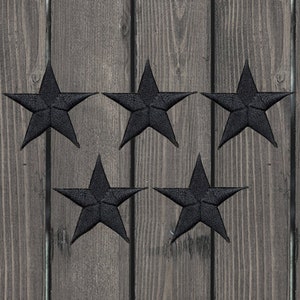 May include: Five black felt star-shaped patches on a wood background.
