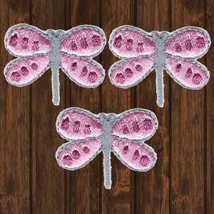 May include: Three pink and gray embroidered dragonfly iron-on patches.