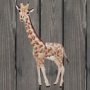 May include: Embroidered iron-on patch of a brown and white giraffe standing on a wood background.