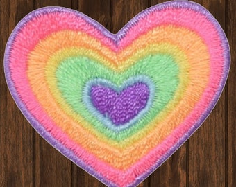 May include: A rainbow heart-shaped patch with a smaller purple heart in the centre. The patch is made of a soft, fuzzy material and is perfect for adding a touch of whimsy to any project.