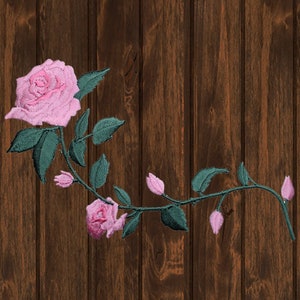 Puede incluir: Una rosa rosa con hojas y tallos verdes sobre un fondo de madera marrón.