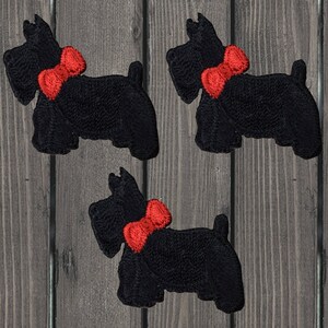 Puede incluir: Tres parches de planchado de fieltro negro de un perro terrier escocés con una pajarita roja.