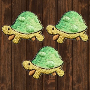 Puede incluir: Tres parches bordados para planchar de tortugas verdes con caparazones amarillos y patas naranjas.