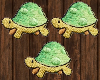 May include: Three embroidered iron-on patches of green turtles with yellow shells and orange feet.
