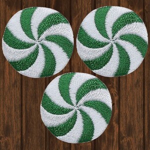 May include: Three green and white peppermint swirl candy cane shaped patches. The patches are embroidered and have a white background with green swirls.