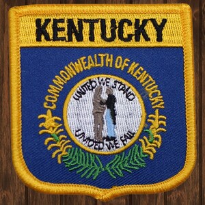 May include: An embroidered patch in blue and gold with the words "Kentucky" and "Commonwealth of Kentucky" and the state seal featuring two figures shaking hands with the words "United We Stand, Divided We Fall".