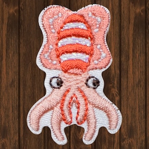May include: A pink and orange embroidered squid patch with white accents. The squid has large eyes and a striped body.