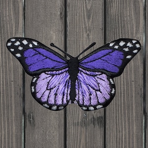 May include: Purple embroidered butterfly patch with black accents and white spots on the wings.