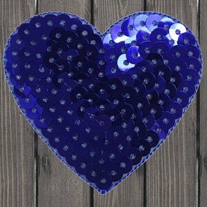 May include: A blue heart-shaped patch made of sequins. The sequins are arranged in a pattern that creates a heart shape. The patch is perfect for adding a touch of sparkle to any project.