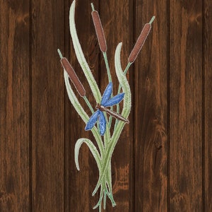 May include: An embroidered patch featuring a blue dragonfly with brown wings and a green stalk of cattails with brown tips.
