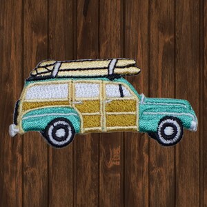 May include: A teal blue and brown vintage station wagon with wood paneling and surfboards on the roof. The car is embroidered on a fabric patch.
