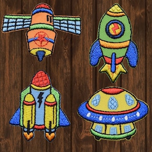 May include: Four embroidered iron-on patches featuring space-themed designs: a spaceship, a rocket, a rocket with boosters, and a flying saucer. The patches are colorful and have a cartoonish style.