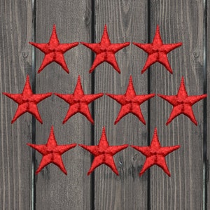 May include: Ten red felt star-shaped embellishments on a wood background.