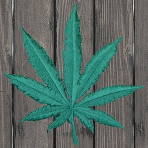 May include: A teal green marijuana leaf with seven points, against a woodgrain background.