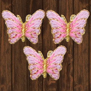 May include: Three pink butterfly iron-on patches with gold embroidery. The butterflies have a delicate, feminine design.