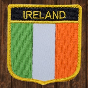 May include: A green, white, and orange embroidered patch with a yellow border and the word "IRELAND" in yellow lettering on a black background.