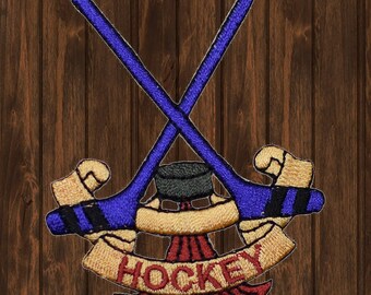 May include: An embroidered patch featuring two crossed hockey sticks, a puck, and a banner that reads "HOCKEY". The patch is blue and black.