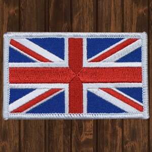 May include: A white embroidered patch featuring the Union Jack flag design. The flag is red, white and blue.